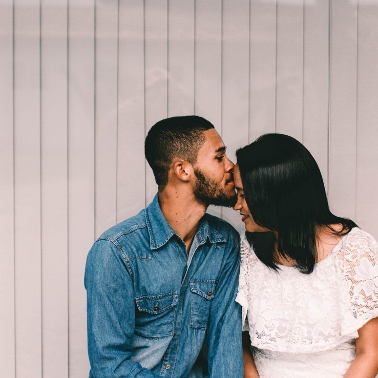 Man kisses woman's forehead
